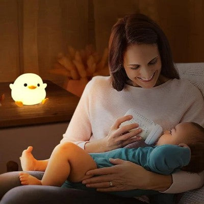 Parent nourrissant bébé près d’une veilleuse rechargeable apaisante.