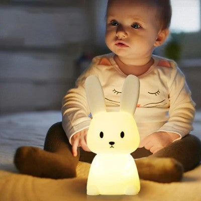 Bébé tenant une veilleuse lapin chaleureuse au coucher.