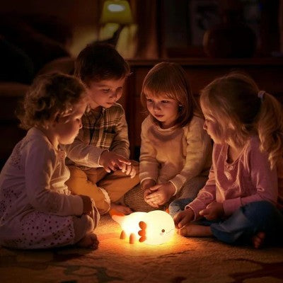 Enfants fascinés autour d’une veilleuse rechargeable lumineuse.