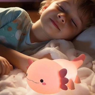 Enfant endormi près d’une veilleuse rechargeable axolotl douce.