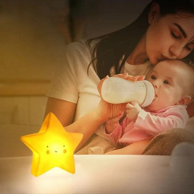 Maman nourrissant bébé près d’une veilleuse bébé étoile.