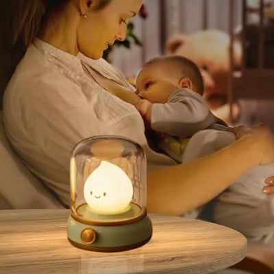 Veilleuse bébé sous cloche éclairant une scène d’allaitement.