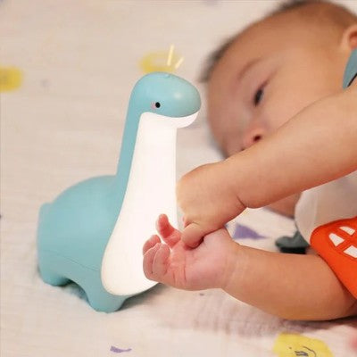 Veilleuse rechargeable dinosaure bleu attirant bébé curieux.