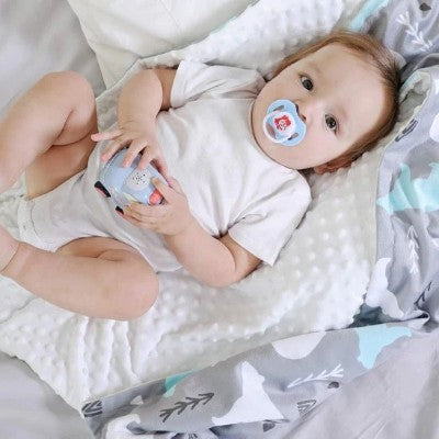 couverture bébé grise et bleue couvrant enfant avec jouet