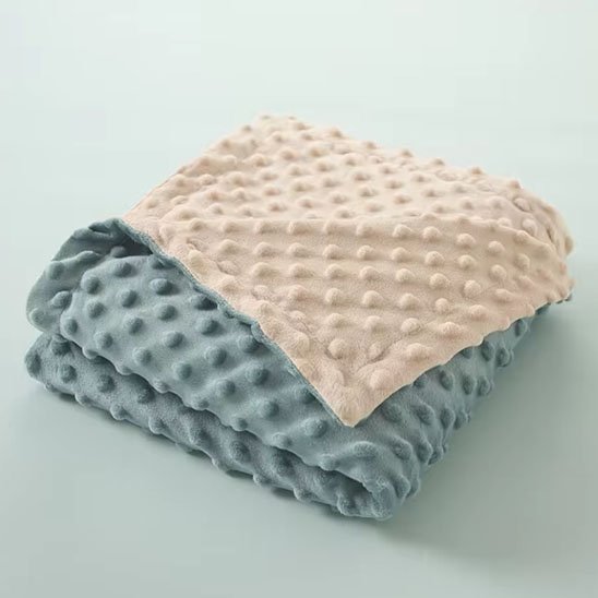 couverture bebe polaire beige et bleue texture douce pliee