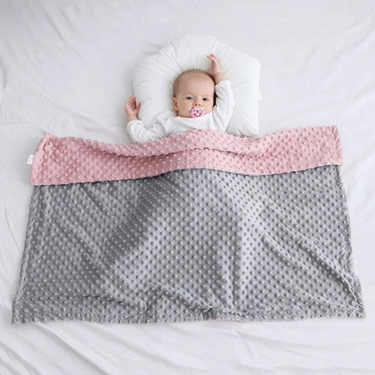 couverture bebe polaire rose et grise sur lit enfant