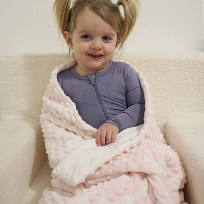 couverture bébé rose et blanche enveloppant enfant souriant