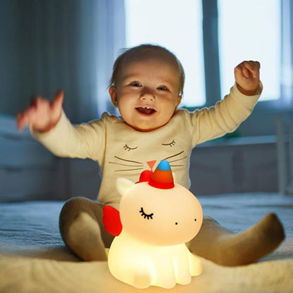 Enfant souriant devant une veilleuse rechargeable licorne lumineuse.