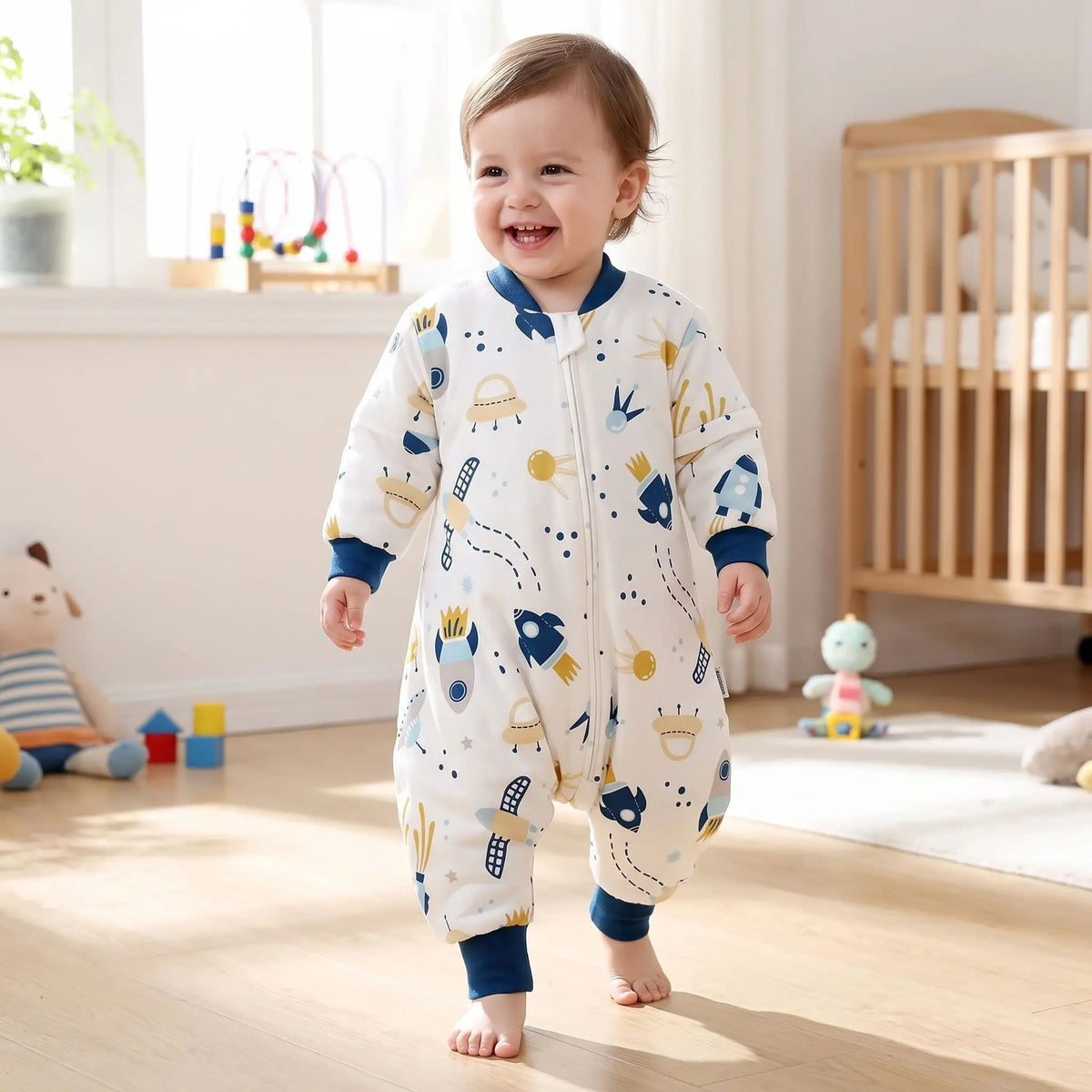 Tout-petit souriant qui marche avec sa gigoteuse avec jambes motif fusées
