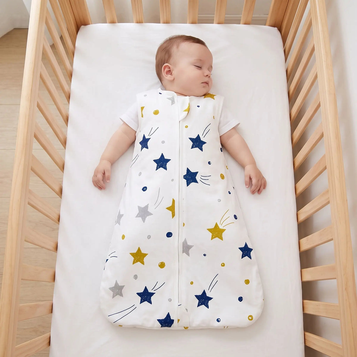Bébé endormi sur le dos en gigoteuse à étoiles, lit dégagé