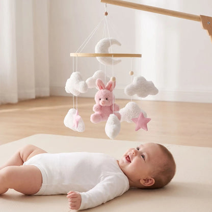 Mobile bébé fille lapin rose suspendu au-dessus d'un bébé éveillé allongé sur un tapis d'éveil