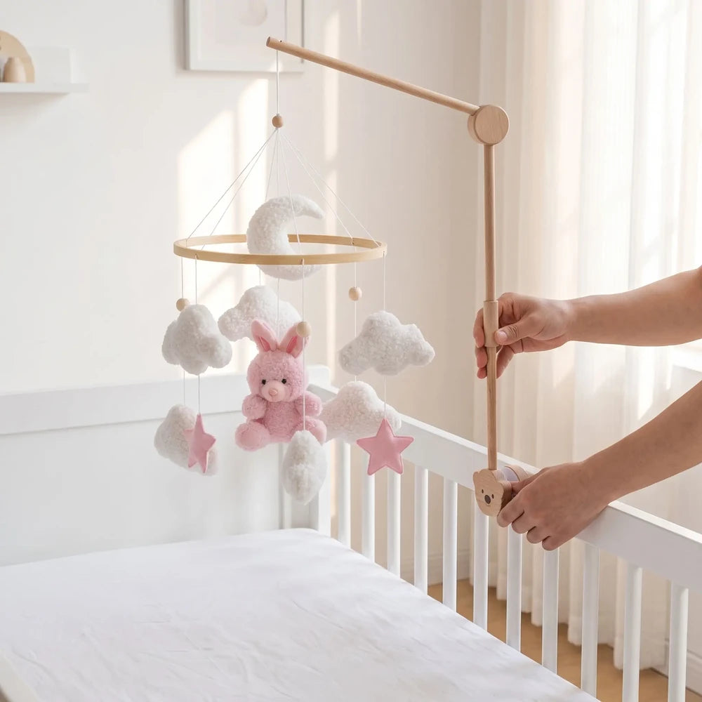 Mobile bébé fille : mains fixant la pince du bras en bois sur le montant d'un lit à barreaux