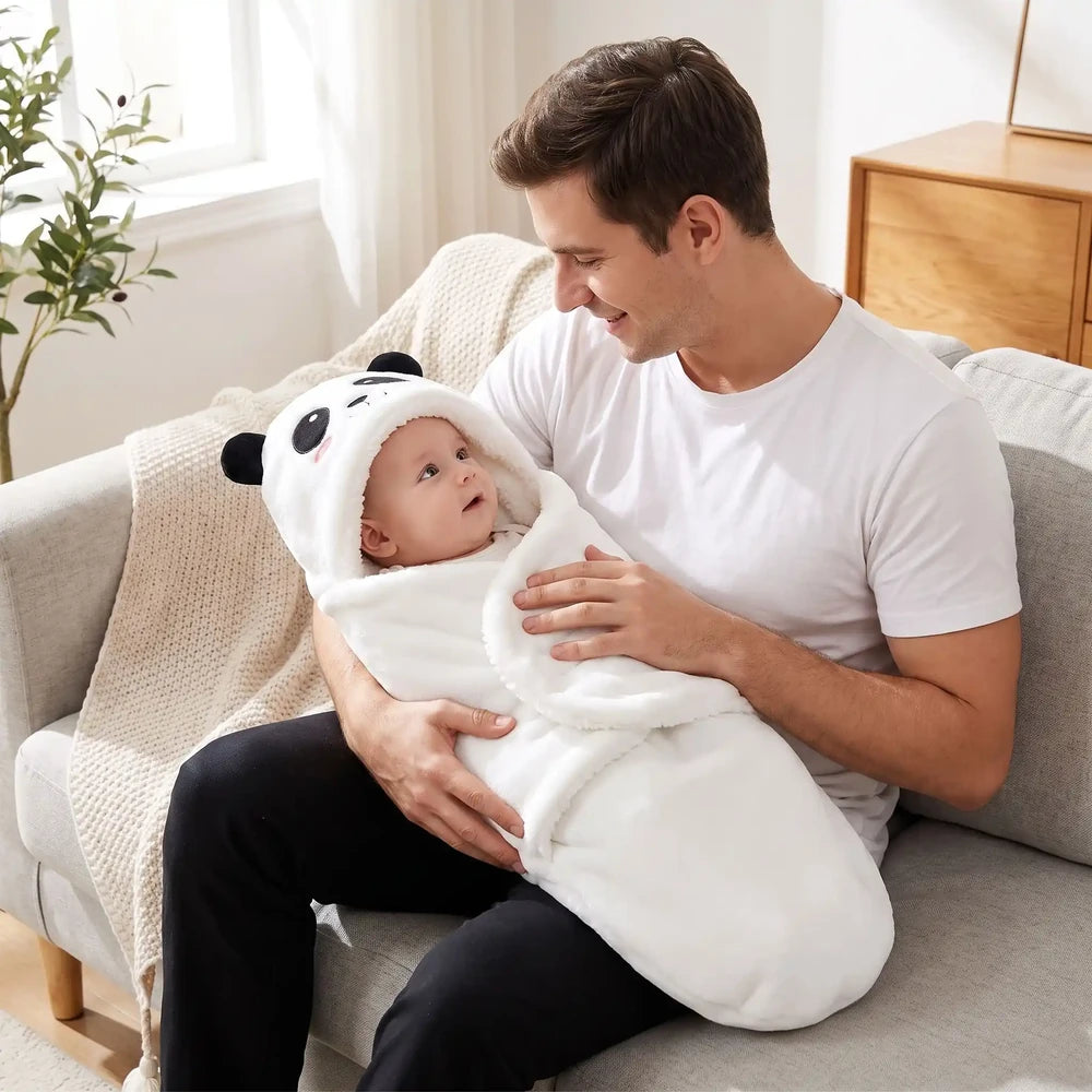 Bébé éveillé dans le nid d'ange bébé blanc à capuche panda, sur les genoux de son papa au salon