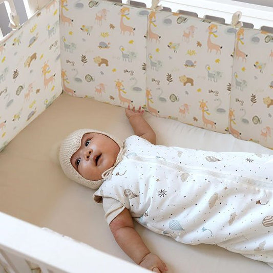 Tour de lit animaux colorés entourant bébé en douceur.