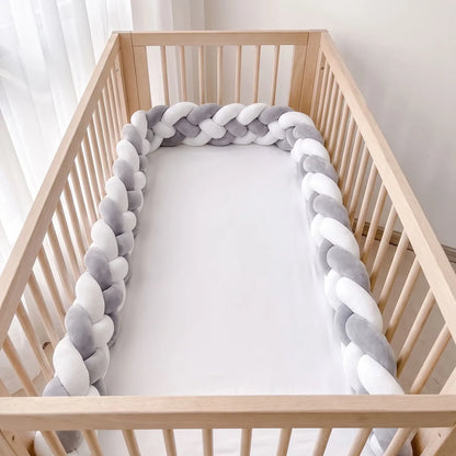Natte à quatre brins grise et blanche dans un lit à barreaux vide