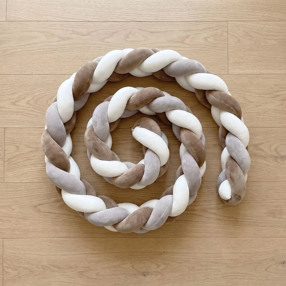 Tresse de lit marron, blanc et gris à 3 brins enroulée sur un parquet clair