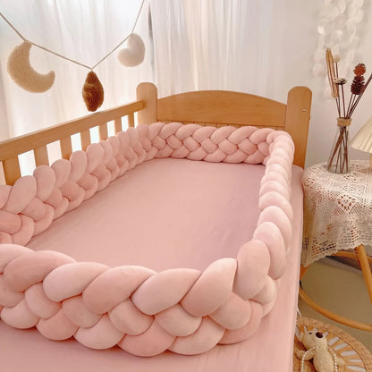 Tresse de lit rose poudré à quatre boudins autour d'un lit à barreaux vide