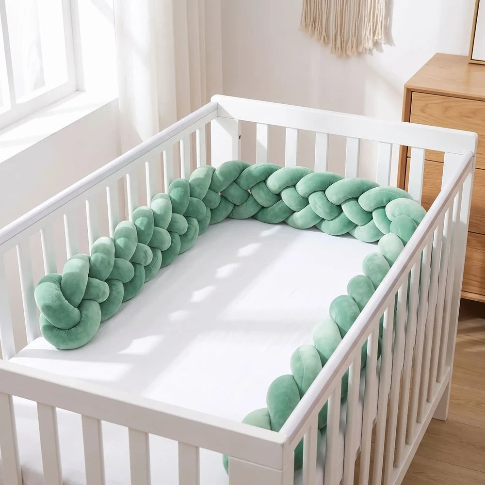 Tresse de lit vert sauge posée sur le matelas le long des barreaux d'un lit blanc vide